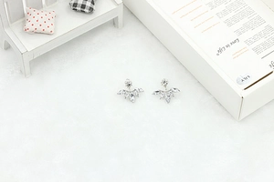 Macro detail of silver marquise zircon flower stud earrings on white velvet background