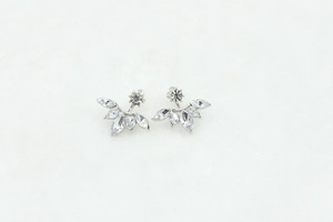Detail of silver daisy earrings with marquise cubic zirconia on white textured background