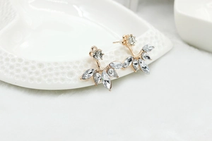 Detail of floral zircon stud earrings on a white heart ceramic tray and soft fur