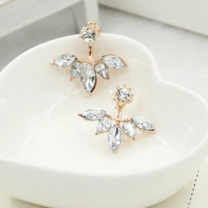 Daisy zircon stud earrings with gold petals in a white heart-shaped ceramic dish
