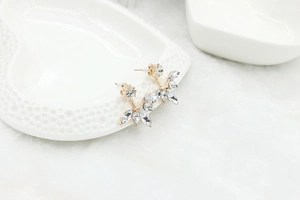 Detailed close-up of leaf-shaped marquise zircon stud earrings on a white heart ceramic dish