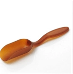 Macro view of a single translucent amber plastic measuring spoon on a white background