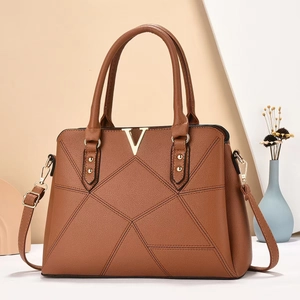 Detail of caramel leather tote with textured finish and V-shaped gold metal hardware