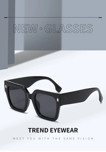 Détail de lunettes de soleil carrées noires avec branches larges et décor doré