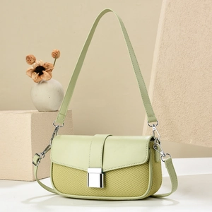 Detail of pistachio green shoulder bag with woven texture, leather flap and metal buckle