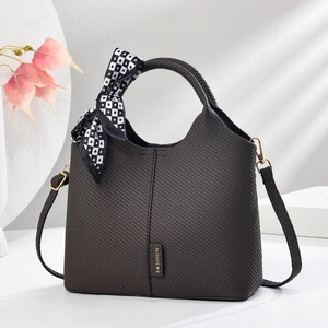 Dark brown woven tote bag with silk scarf handle on a minimalist geometric display