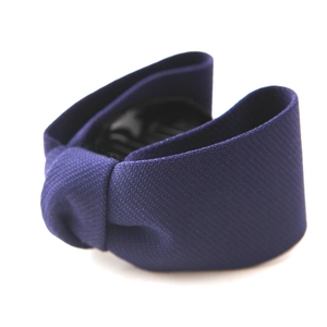 Detailed view of a dark blue fabric bow hair clip with a sturdy black plastic inner grip