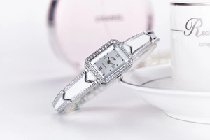 Macro detail of silver square quartz watch featuring a rhinestone bezel and steel chain band