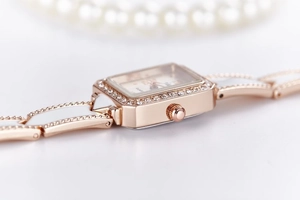 Detail of rose gold square watch case with sparkling rhinestones and metal crown