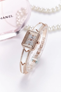 Detailed side view of a rectangle rose gold quartz watch with crystals and white enamel band