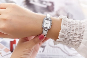 Elegant women's square silver quartz watch with rhinestone accents worn on wrist