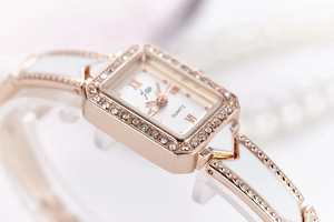 Macro shot of rose gold rectangular watch dial with rhinestones and white metal strap links