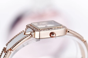 Detail of rose gold square watch face with crystal bezel and ceramic link bracelet