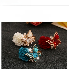 Close-up of vintage bohemian rings featuring resin roses and butterfly crystal details