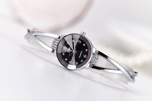 Detail of silver steel watch band with crystals and black quartz dial on white surface