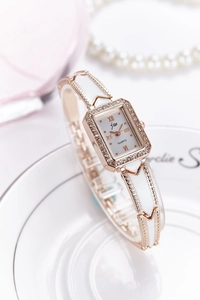 Close-up of a rose gold square quartz watch with crystal bezel and enamel bracelet strap