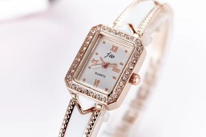 Close-up of rose gold square watch with crystal bezel and white ceramic link strap