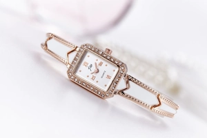 Detail of rose gold square watch with crystal inlay and Roman numeral dial for women