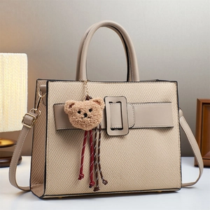 Elegant beige woven tote bag with khaki leather trim and brown plush bear charm detail
