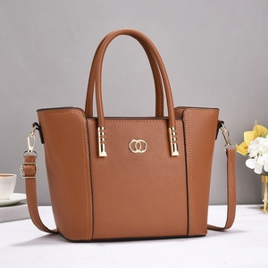 Detailed macro view of the brown lychee grain texture and gold ring buckle of the tote bag