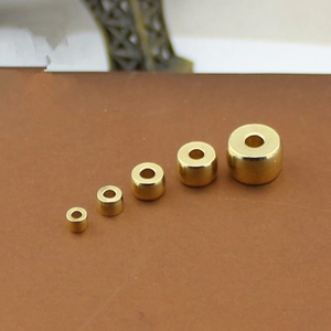 Brass barrel beads in five sizes arranged on a brown surface for DIY jewelry making