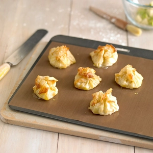 Reusable non-stick brown baking sheet with golden pastries on a professional oven tray