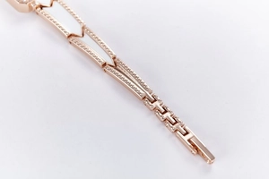 Macro shot of rose gold metal link watch strap with fine textured grain and glossy finish