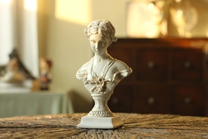 Detail view of white Venus bust statue with fine hair textures and floral relief