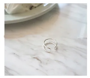 Detailed view of minimal double-line S925 sterling silver open ring on marble background