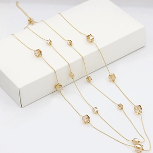 Elegante collar largo dorado con cubos de cristal champán en expositor blanco