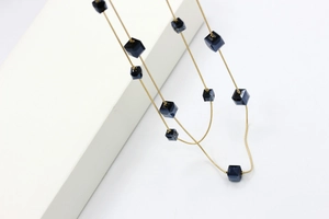 Detalle de collar de cadena de serpiente dorada con cubos de cristal azul profundo