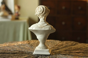 Detailed back view of a Venus head sculpture in white resin with vintage texture on wood