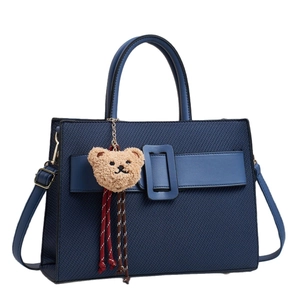 Retro navy blue woven underarm bag with top handles and a cute plush bear charm