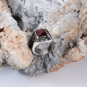 Vintage stainless steel ring with square red gemstone on a textured rock base