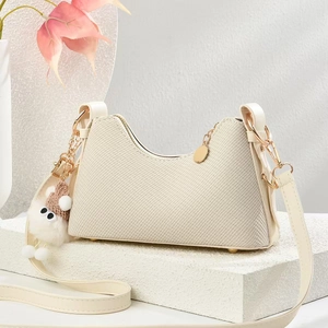 Détail du sac bandoulière tissé crème avec fermeture dorée et breloque ours en peluche