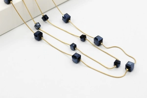 Detalle de cadenas de serpiente doradas con cuentas de cristal de cubo azul oscuro