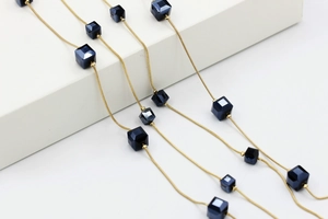 Detalle de cadena de serpiente dorada con cuentas de cristal azul y estilo geométrico