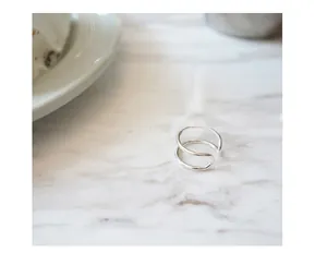 Macro detail of minimalist S925 sterling silver double-line open ring on marble background