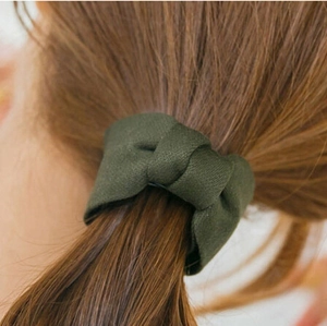 Deep green fabric bow hair tie accessory on a ponytail for women and girls