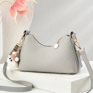 Sac baguette en sergé gris avec bordure en cuir et breloque peluche sur socle pierre