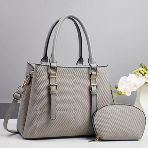 Gray textured woven handbag and small pouch set with gold hardware on a minimalist background