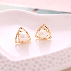 Elegant gold hollow triangle stud earrings with center pearl in a heart ceramic dish