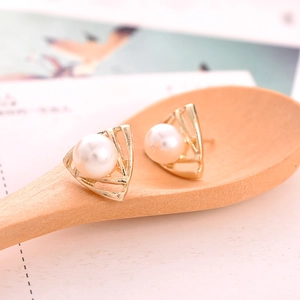 Elegant gold triangle frame earrings with white pearls displayed on a rustic wooden spoon