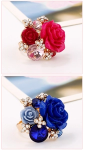 Detail view of resin rose rings in red and blue with gold-tone adjustable bands