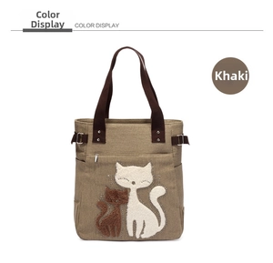 Detail of khaki canvas tote bag featuring 3D cartoon cat patches and sturdy web handles