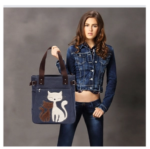 Detail of dark blue canvas tote bag featuring cute cat embroidery and brown handles