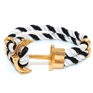Macro detail of nautical rope bracelet featuring a polished gold-finished anchor clasp