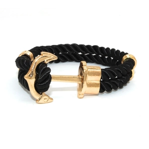 Detail of nautical anchor clasp in gold with black braided cord rope bracelet