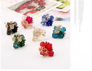 Flat lay of colorful resin flower rings with crystals in red, blue, green, and pink