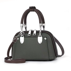 Detailed close-up of dark green lychee grain leather with brown handles and silver hardware